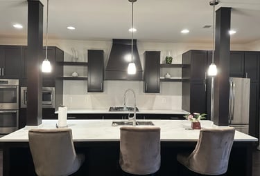 Modern kitchen with brown-veined quartz island and white 3D wave backsplash.