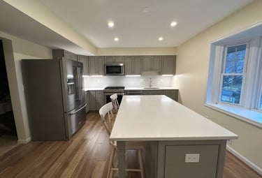 Grey kitchen remodel with quartz counters, stainless steel sink, and brown LVP flooring.