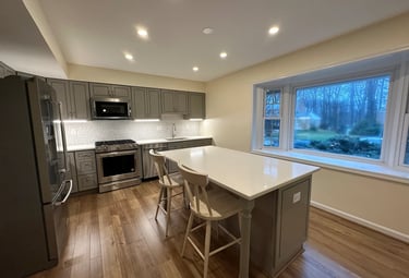 A beautifully updated kitchen featuring gray shaker cabinets, quartz countertops, and warm LVP