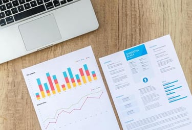 Una computadora portátil y un currículum profesional con gráficos de datos sobre un escritorio.