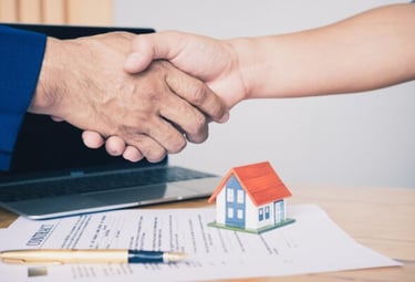 Agente inmobiliario dándose la mano sobre un modelo de contrato para comprar o rentar propiedad