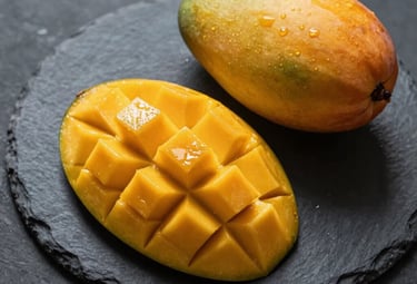 A top-down photographic shot of sliced Chaunsa mango on a dark stone slab, showing the juicy, deep yellow pulp and a small bowl of fruit. The styling is minimalist and luxurious, capturing the honey-sweet essence of the fruit.