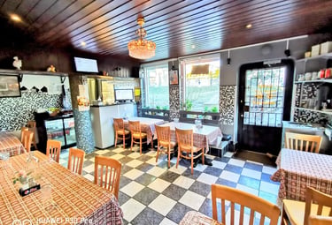 Cozy restaurant interior featuring checkered floors, wooden tables, and a vintage crystal chandelier.