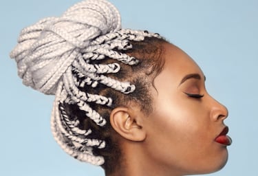 a woman with a large hairdo of white braids on a sky-blue background