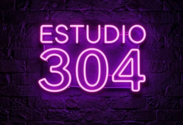 A sophisticated low-angle photograph of a premium adult modeling studio background in Latin American / Global. In the center, a glowing neon sign on a dark brick wall clearly reads ESTUDIO 304 in bright neon pink and electric purple colors. Seductive dark purple atmosphere, highly detailed, high-end adult entertainment aesthetic.