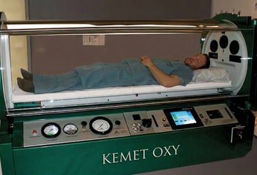 A patient lies inside a Kemet Oxy monoplace hyperbaric oxygen therapy chamber for medical treatment.