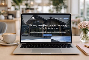 Laptop displaying a framing and siding construction website on a desk with coffee and flowers.