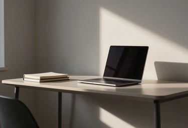A minimalist North American home study area with a sleek desk, a laptop, and a small stack of journals, lit by soft afternoon sun.