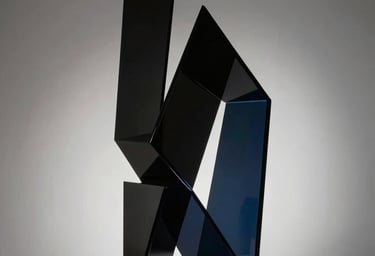 Photography of a minimalist abstract glass sculpture, sharp geometric edges, soft light passing through, rich black and midnight blue tones, North American gallery style.