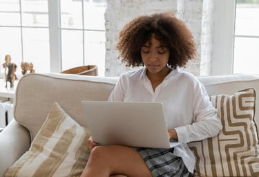 A single mom working on her side hustle on her laptop in her living room while her kid is in school.