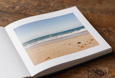 A high-quality lifestyle photograph of a printed photo album laying open on a rustic wooden table, Soft Sand and Deep Brown color palette.