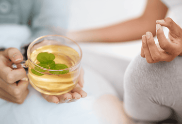 blended image of a woman holding a glass of tea and a glass of tea another woman meditating