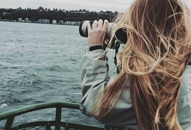 a woman taking a picture of a boat in the water