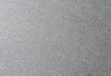 A close-up photographic texture of a smooth grey stone surface, soft natural lighting, minimalistic and clean, International / Western.