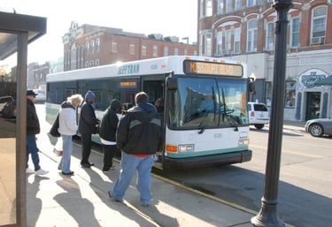 A group of people at a bus stop boarding a Jefferson City bus