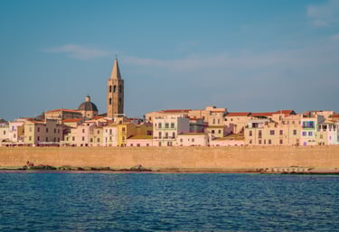 Seafront and historic center of Alghero, Sardinia, seen from the sea at sunset.