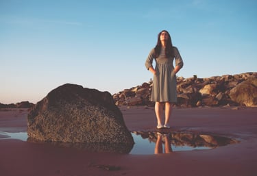 photo of woman looking up at the sky on a beach at sunset