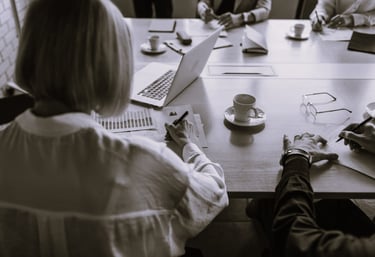 Femme assise à une table avec plusieurs personnes qui présente un projet commercial
