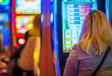 A blonde woman plays a glowing slot machine in a brightly lit Las Vegas casino.
