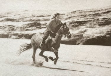 Black and white photograph in silver and Platinum of a woman riding a horse on a beach