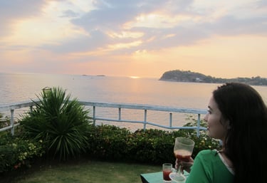 a woman sitting on a lawn chair with a glass of wine overlooking the ocean