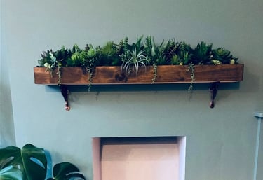 Rustic indoor fireplace featuring a succulent wooden mantle shelf, monstera plant, and lit candles.