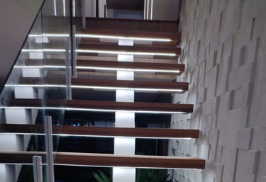 Vista de cima para baixo dos degraus de madeira de uma escada flutuante, destacando a iluminação de LED embutida em cada degr