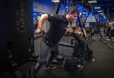 Trener instruuje podopiecznego gdy ten wykonuje ćwiczenie na siłowni.