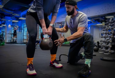 Trener instruuje kobietę przy treningu z kettlebell.