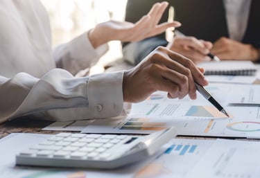 picture of hands of 3 people worgin on documents a table 