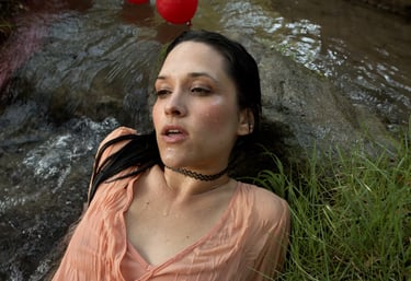 a woman in a pink shirt is laying in water in a music video