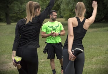 Trener stojący przed dwiema dziewczynami uprawiającymi stretching.