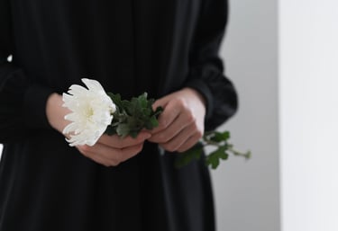 Woman gently holding a white chrysanthemum flower in remembrance.