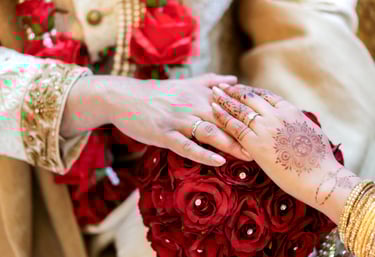 pakistani bride and grooms hands wearing wedding rings against the bride's bouquet as the backdrop 