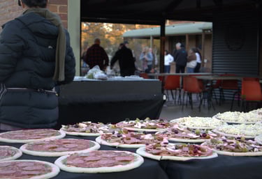 rows of pizzas being prepared by staff. Pizza catering