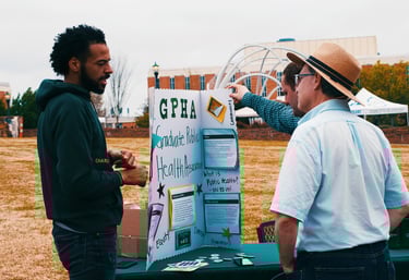 People at UNC Charlotte conversing at the Graduate Public Health Association stall at the Earth Day Festival.