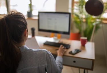 a woman sitting at a desk with a computer and a ball