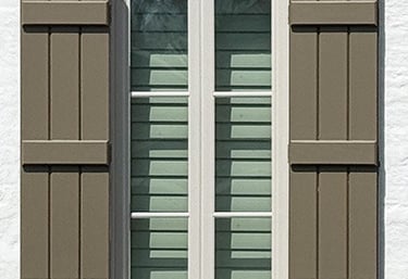 exterior board and batten shutters in brown on white brick