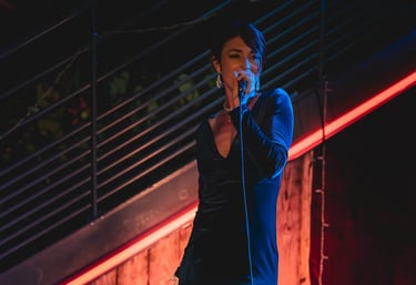Jessie BaréKa interprète une chanson sur scène en robe noire élégante.