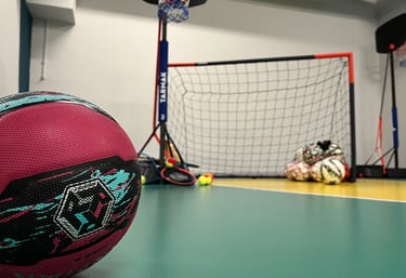 Primo piano di un pallone da basket rosa su un campo multisport nella palestra Move 2 Grow a Milano, con canestro, porta e al