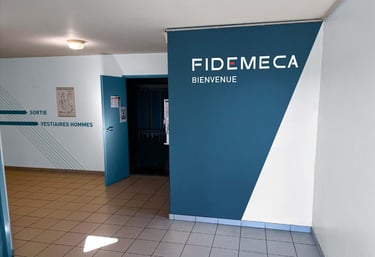 un couloir avec un panneau bleu et blanc indiquant Fidemeca