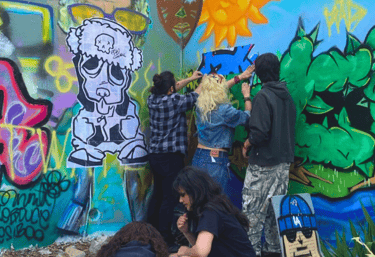 artist leading young people installing a wheat paste mural