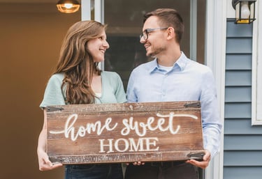 Happy homeowners with home sweet home sign, representing the excitement of first-time home buyers