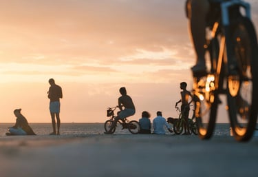 People enjoying the sunset at the beach in Mauritius, with silhouettes of bikers in the foreground.
