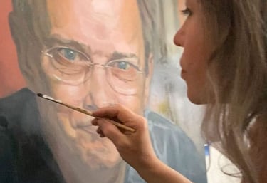 Close-up on Stefanie adding last details to oil portrait of smiling man.