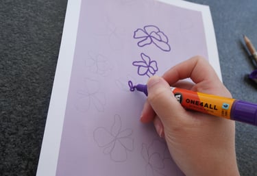 Hand drawing a custom floral pattern design with a purple marker.
