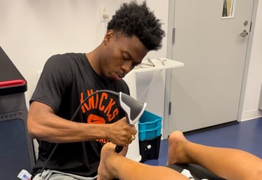 Sports medicine therapist performing leg recovery therapy using shockwave treatment on athlete