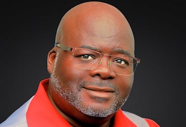 Headshot of a man with glasses wearing a red shirt and gray vest