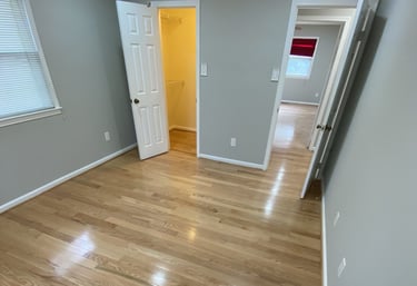 Bedroom with closet doors, smooth hardwood floors, and neutral paint