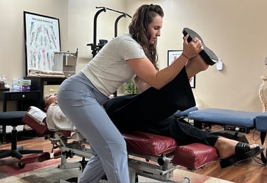 Chiropractor performing nerve tension test on patient laying face up on chiro table.